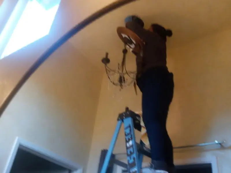 Electrician installing a chandelier in a Auburn residence